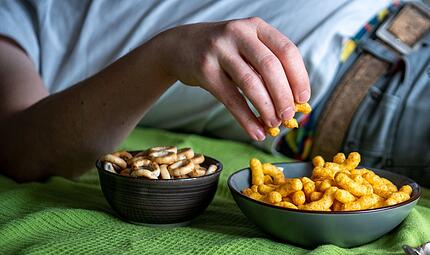 Mann isst auf einem Sofa Chips Mann isst auf einem Sofa Chips