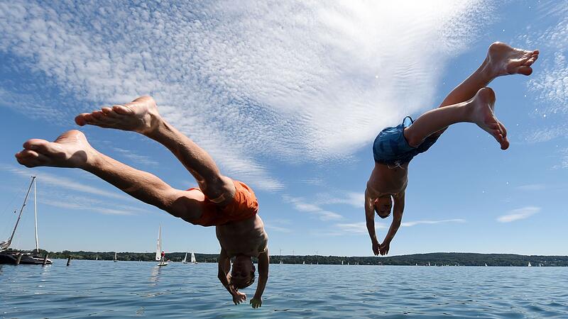 Zwei junge Männer springen am Starnberger See ins Wasser