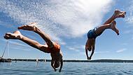Zwei junge Männer springen am Starnberger See ins Wasser