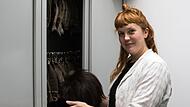 Chefmaskenbildnerin Alicia-Lara Müller vor einem der großen Metallschränke, in denen der Perücken-Schatz des Landestheaters aufbewahrt wird.