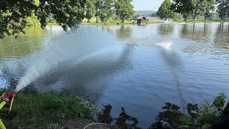 Die Neustadter Feuerwehr spritzt Wasser zur&uuml;ck in einen Teich bei Ketschenbach. Die Fische freuen sich.