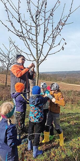 Obstbaumbeauftragter Wolfgang Reidelbach bringt gemeinsam mit den Kindern die Namensschilder f&uuml;r die neuen Obstbaumpaten an.