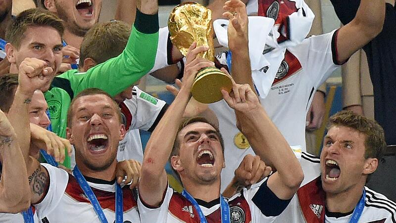 ARCHIV - 13.07.2014, Brasilien, Rio de Janeiro: ARCHIV - 13.07.2014, Brasilien, Rio de Janeiro: Philipp Lahm (M) aus Deutschland jubelt mit dem WM-Pokal zwischen seinen Teamkollegen Lukas Podolski (l) und Thomas Müller (r) während der Siegerehrung... ARCHIV - 13.07.2014, Brasilien, Rio de Janeiro: ARCHIV - 13.07.2014, Brasilien, Rio de Janeiro: Philipp Lahm (M) aus Deutschland jubelt mit dem WM-Pokal zwischen seinen Teamkollegen Lukas Podolski (l) und Thomas Müller (r) während der Siegerehrung...