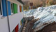 Im Hintergrund mit Folie abgedeckt ist die neue Hangbefestigung zu sehen. Im Vordergrund die Gestaltung der Hangbefestigung an der oberen Seite des Kindergartens mit neu eingebrachter Drainage.Forchheim & Fränkische Schweiz