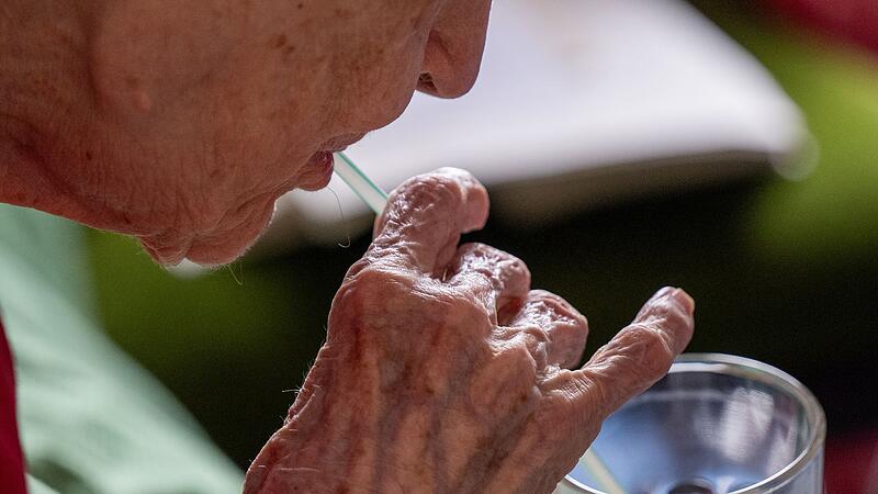 Eine Seniorin trinkt mithilfe eines Strohhalms