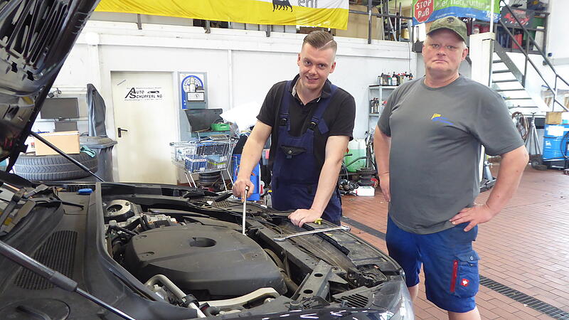 Tobias Hofmann (l.) und Mario Sch&uuml;pferling sehen sich in der Autowerkstatt  in Reifenberg einen Motor an.
