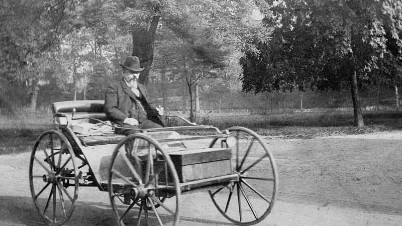 Das  historische Foto zeigt  den Erfinder Andreas Flocken auf seinem Elektrowagen in der Umgebung des Ernstplatzes.