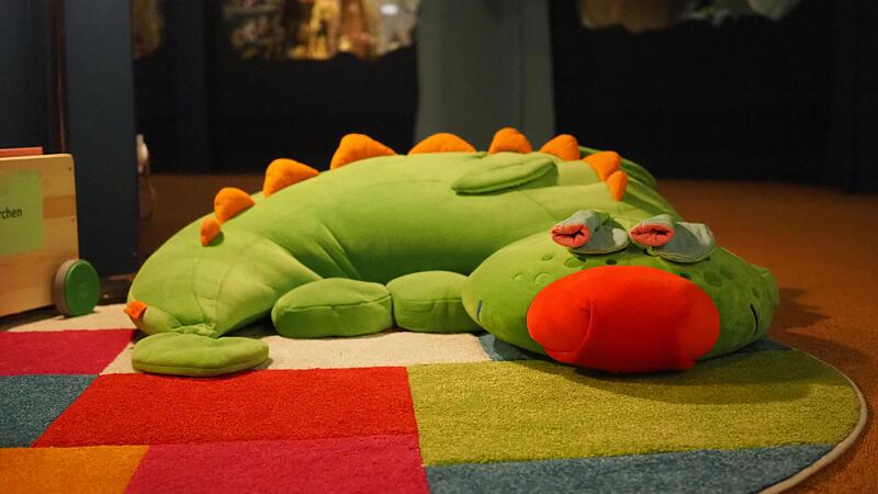 Exponat des Monats im Spielzeugmuseum Neustadt ist der Drache Fridolin, produziert von der Firma Haba. Er scheint schon auf die jungen Leseratten in der Leseecke zu warten.