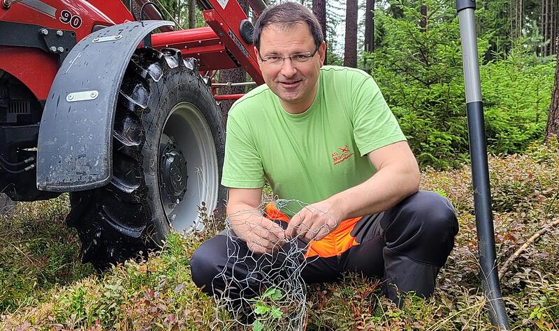 Der Politiker ist auch Waldbauer. Martin Sch&ouml;ffel wickelt hier ein Drahtgeflecht um eine kleine Eiche, um sie vor dem Rehverbiss zu sch&uuml;tzen. Im Hintergrund ist sein roter Case-Traktor zu sehen.