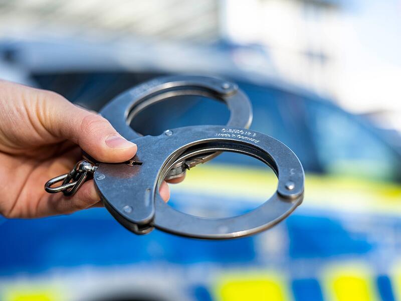 Handschellen vor Polizeiwagen