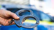 Handschellen vor Polizeiwagen