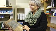 Susanne Karges k&uuml;mmert sich um die Archive der acht Rh&ouml;nallianz-Gemeinden, hier zeigt sie ein altes Buch aus dem Archiv in Geroda.