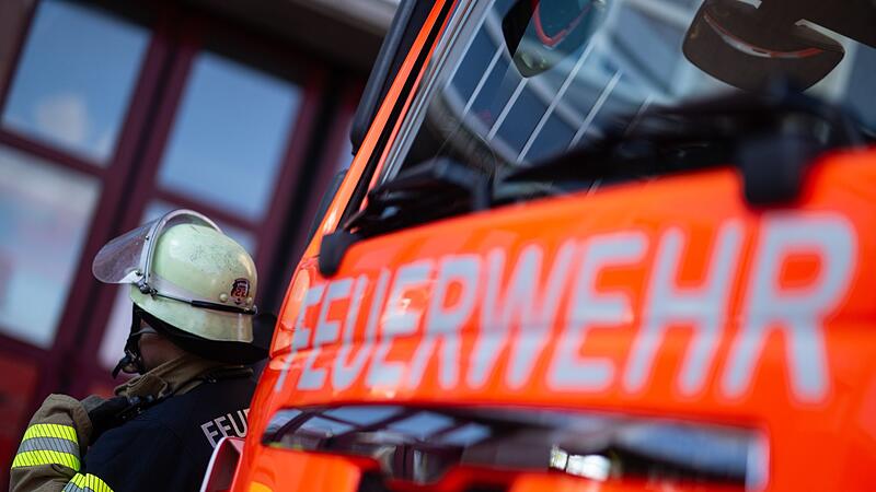 Feuerwehrmann steht neben einem Feuerwehrauto (Symbolbild)