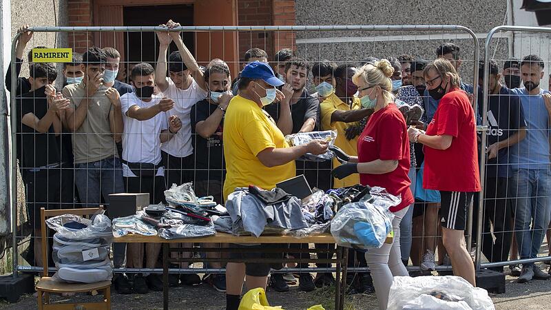 Litauer verkaufen Dinge an Migranten, die hinter dem Zaun eines Flüchtlingslagers stehen. Die Grenzschutzagentur Frontex verstärkt angesichts der steigenden Zahl illegal Einreisender ihre Unterstützung für Litauen an der Grenze zu Belarus. Litauer verkaufen Dinge an Migranten, die hinter dem Zaun eines Flüchtlingslagers stehen. Die Grenzschutzagentur Frontex verstärkt angesichts der steigenden Zahl illegal Einreisender ihre Unterstützung für Litauen an der Grenze zu Belarus.