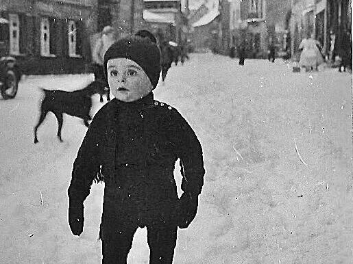 Der dreij&auml;hrige Manfed 1936 vor dem Modegesch&auml;ft seines Gro&szlig;vaters in der Spitalgasse. Links dem Gesch&auml;ft gegen&uuml;ber eine Hakenkreuz-Fahne, im Hintergrund sein geliebter Dobermann &bdquo;Pilar&ldquo;.
