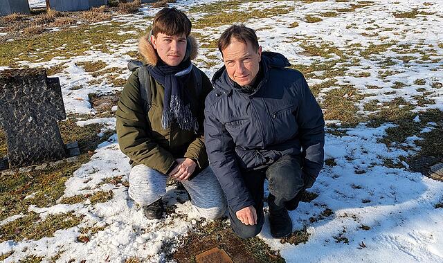Enkel aus Polen besucht Grab im Soldatengräberfeld Tomasz Kurtz (rechts) mit Sohn Paweł am Grab seines 1939 verstorbenen Großvaters Tadeusz Kurtz
