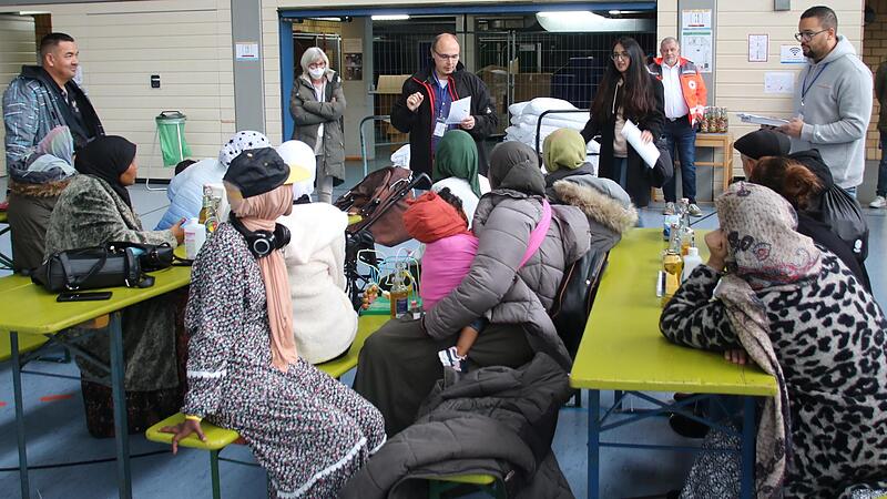 Frank Gerstner (stehend, Dritter von links), der Leiter der Sozialen Dienste beim Roten Kreuz, hei&szlig;t die 20 Asylbewerber in der Lichtenfelser Berufsschulturnhalle willkommen. Anschlie&szlig;end werden den Afghanen und Somaliern familienweise die proviso...