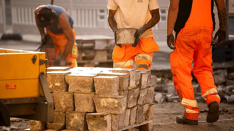 Bauarbeiter arbeiten bei Hitze an Straßenbahn-Gleisen