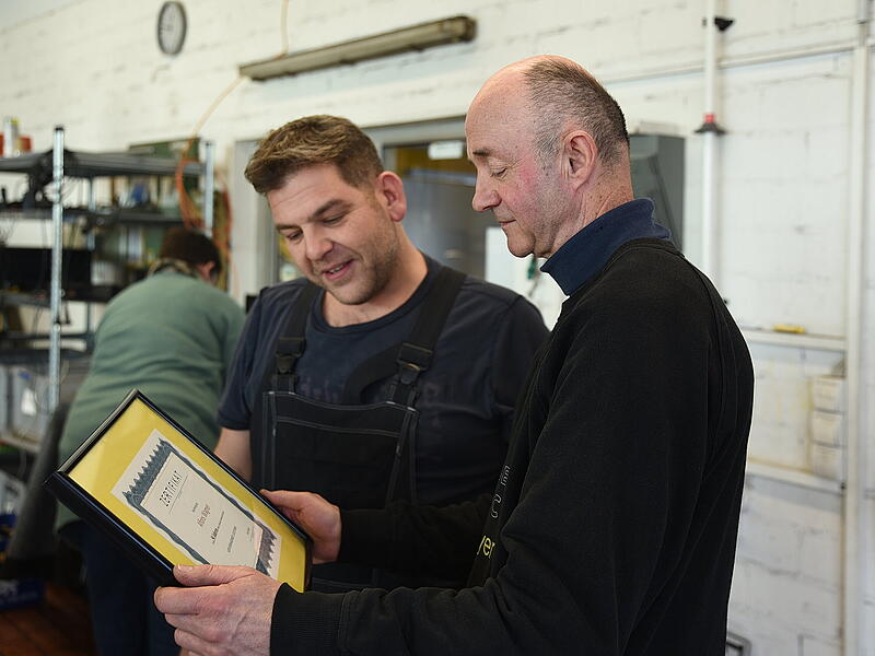 Juniorchef Peter Bayer (l.) &uuml;berreicht Alfons Wagner das Zertifikat f&uuml;r 50 Jahre Zugeh&ouml;rigkeit zum selben Betrieb in Effeltrich.
