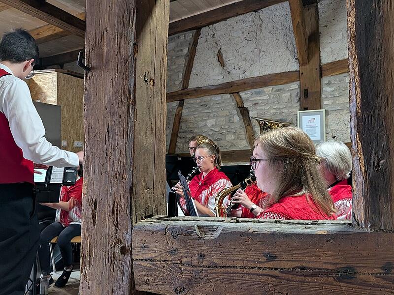 Dirigent und Musikerinnen sind eingerahmt.