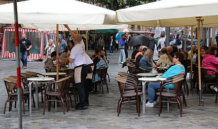 Am Gr&uuml;nen Markt sind die Sitzpl&auml;tze trotz Nieselregens gut besucht.