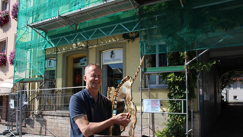 Apotheker Sebastian Hose mit dem Aushängeschild der Einhornapotheke, das wegen des Schutzgerüstes am angeblich einsturzgefährdeten Haus abmontiert wurde. Um einen langwierigen Rechtsstreit zu vermeiden, zieht er mit seiner Apotheke Ende September ... Apotheker Sebastian Hose mit dem Aushängeschild der Einhornapotheke, das wegen des Schutzgerüstes am angeblich einsturzgefährdeten Haus abmontiert wurde. Um einen langwierigen Rechtsstreit zu vermeiden, zieht er mit seiner Apotheke Ende September ...