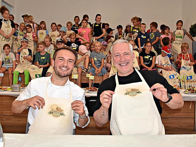 Nicht nur die Kinder hatten viel Spa&szlig; an der Aktion: Landrat Jonas Gleich und Sternekoch Alexander Herrmann signierten Sch&uuml;rzen und erhielten als Dank jeweils eine Sch&uuml;rze, auf der alle Kinder unterschrieben hatten