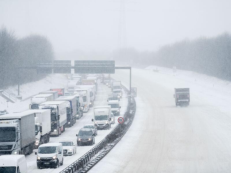 LKW und Autos stehen bei Schnee im Stau
