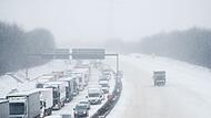 LKW und Autos stehen bei Schnee im Stau