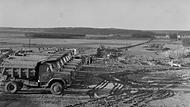 Ein Blick auf die Trasse der künftigen A3 aus Süden Richtung Medbach. Die Lastwagen der Marke Magirus Deutz der Firma Friedrich Glass stehen aufgereiht auf der Baustelle.