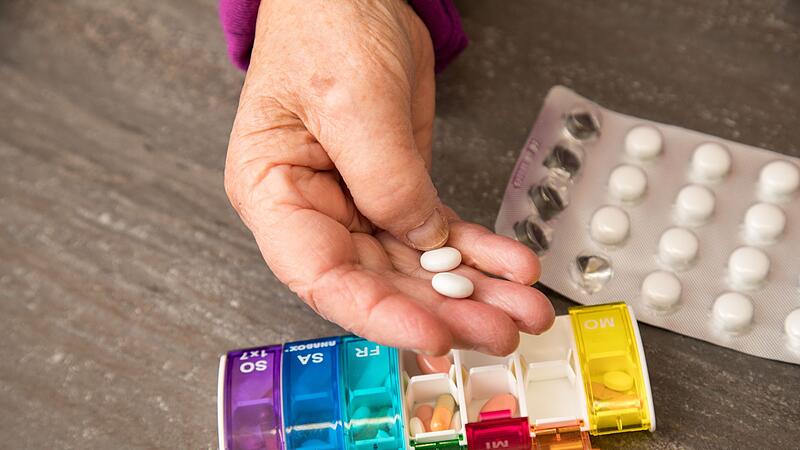 Seniorin nimmt Tabletten aus einer Pillendose