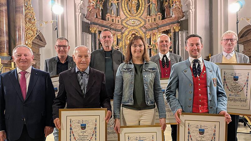 : Landrat Thomas Bold (links) mit den Kulturehrenbrief-Empf&auml;ngern (von links) Heiko Krakofsky (Haard), Michael Schultz (Fuchsstadt), Peter Scherpf (Diebach), Bianca Greubel (Ma&szlig;bach), Walter Borst (Aschach), Bernd Borst (Stangenroth) und Karl Hahn (Bad Br&uuml;ckenau); nicht anwesend war Stefan Roth (Elfershausen)