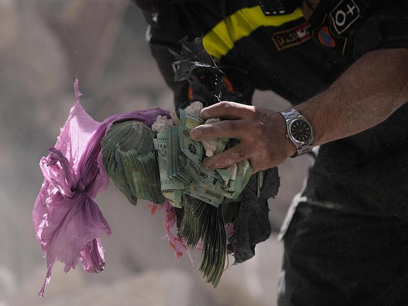 Ein Helfer h&auml;lt Geldb&uuml;ndel aus den Tr&uuml;mmern eines zerst&ouml;rten Geb&auml;udes, das bei einem israelischen Luftangriff getroffen wurde. Die Krise im Nahen Osten wird sich bald auf die Finanzen Bayerns auswirken.