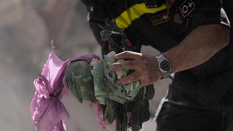 Ein Helfer h&auml;lt Geldb&uuml;ndel aus den Tr&uuml;mmern eines zerst&ouml;rten Geb&auml;udes, das bei einem israelischen Luftangriff getroffen wurde. Die Krise im Nahen Osten wird sich bald auf die Finanzen Bayerns auswirken.