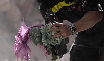 Ein Helfer h&auml;lt Geldb&uuml;ndel aus den Tr&uuml;mmern eines zerst&ouml;rten Geb&auml;udes, das bei einem israelischen Luftangriff getroffen wurde. Die Krise im Nahen Osten wird sich bald auf die Finanzen Bayerns auswirken.