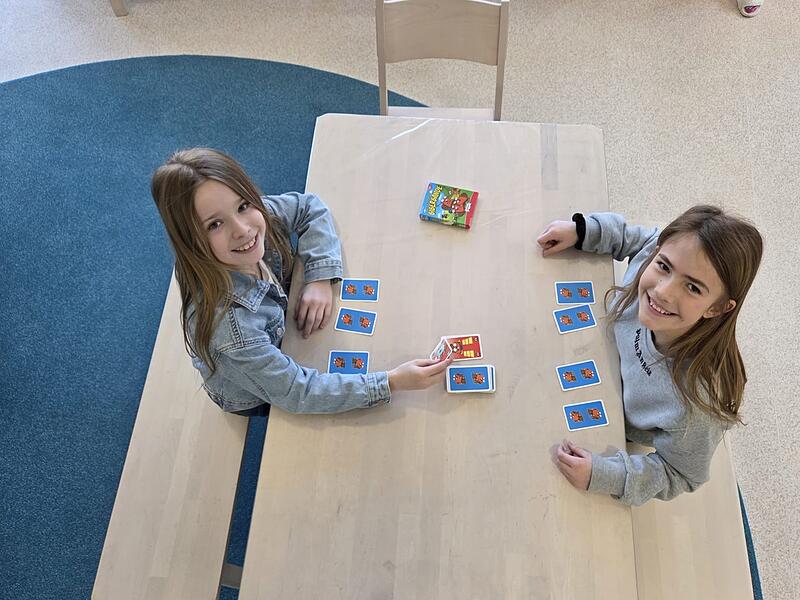 Die Sch&uuml;lerinnen Marlene und Jette (links) vertreiben sich im Rahmen der Nachmittagsbetreuung die Zeit mit einem Kartenspiel, bis es in der Grundschulmensa in Priesendorf zum Mittagessen geht.