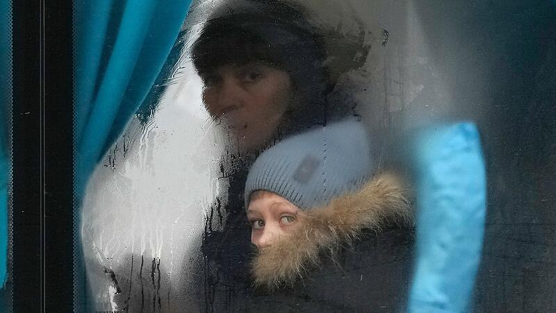 Eine Frau und ein Kind schauen aus dem Fenster eines Busses, als sie Sievierodonetsk in der Region Luhansk in der Ostukraine verlassen. Der russische Präsident Wladimir Putin kündigte am Donnerstag eine Militäroperation in der Ukraine an und warnte andere Länder, dass jeder Versuch, sich in die russische Aktion einzumischen, zu "Konsequenzen führen würde, die Sie noch nie gesehen haben."