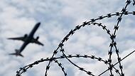 Ein Flugzeug hebt am Flughafen BER hinter einem Zaun mit Natodraht ab. Kanzler Scholz möchte, das Schwerkriminelleauch nach Afghanistan abgeschoben werden.