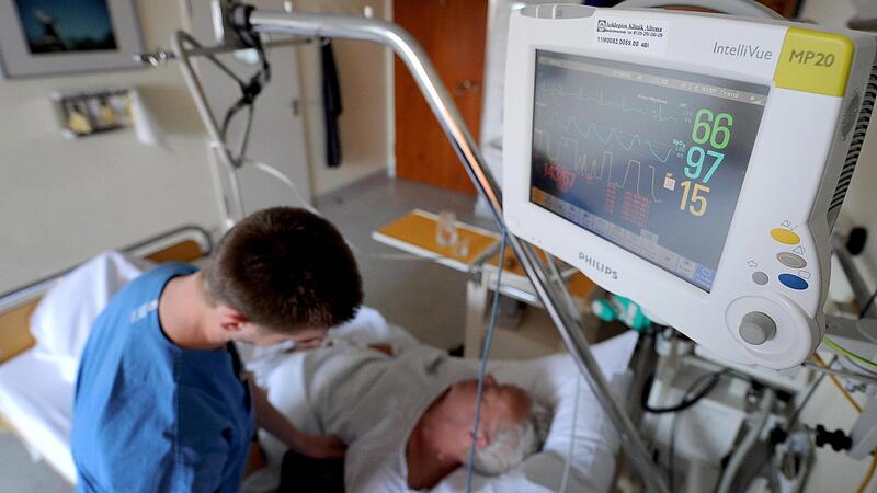 Behandlung in der Klinik: Ein Krankenpfleger &uuml;berpr&uuml;ft die Messinstrumente bei einem Schlaganfallpatienten.