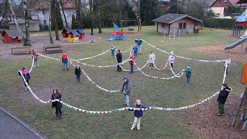 Stolz pr&auml;sentieren die M&auml;dchen und Jungs die riesige Faschingsgirlande im Garten der R&ouml;dentaler Kita Lienhard Fuchs.