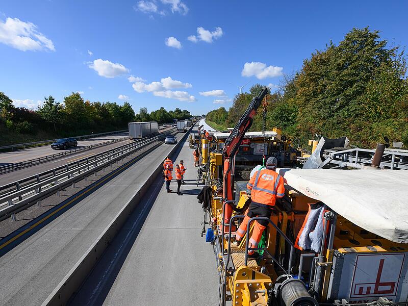 Straßenbauer sind auf einer Autobahn-Baustelle  mit dem halbseitigen Betoneinbau beschäftigt. Dieser ist nicht nur technologisch, sondern auch für die Baustellenverkehrsführung besonders interessant.