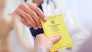 Ein Arzt nimmt den Impfausweis seiner Patientin entgegen