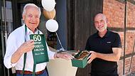 Geschäftsführer Benjamin Kube (rechts) überreicht an Rainer Kober den „Goldbarren“ zum 60-jährigen Bestehen unter dem Titel „60 Jahre Attacke“.
