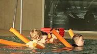 Mit Schwimmnudeln wagen sich diese vier Buben schon alleine ins tiefe Wasser.