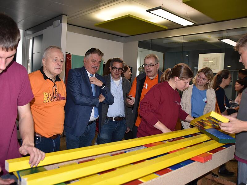 Die Azubis der Schreinerei Bodenschlägel, Fabian, Carolin und Tobias, setzen die bemalten Bretter und Leisten zu einer Sitzbank zusammen - mit im Bild Wolfgang Krügel, Landrat Klaus Peter Söllner, Andreas Schobert, Jürgen Bodenschlägel und Mia Daum.
