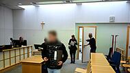 Der Angeklagte wird von zwei Polizeibeamten in den Gerichtssaal geführt.