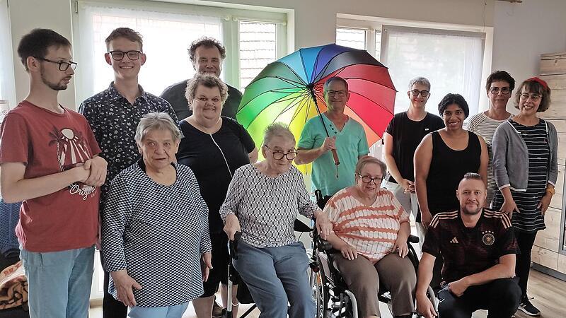 In der Mitte mit Regenbogenschirm Reinhard Kuhn im Kreise der Bewohner, knieend Marco Raithel (Gruppenleiter), links neben Reinhard Kuhn Dominik Hübner (Wohnstättenleitung), rechts Susan Stade (Geschäftsführender Vorstand), daneben Monika Fella (...