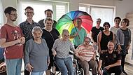 In der Mitte mit Regenbogenschirm Reinhard Kuhn im Kreise der Bewohner, knieend Marco Raithel (Gruppenleiter), links neben Reinhard Kuhn Dominik Hübner (Wohnstättenleitung), rechts Susan Stade (Geschäftsführender Vorstand), daneben Monika Fella (...