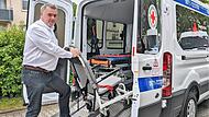 Andreas Klein, der neue Leiter des Rot-Kreuz-Patientenfahrdienstes, beim Einrichten eines Transportfahrzeugs mit Krankenliege und Krankenstuhl.