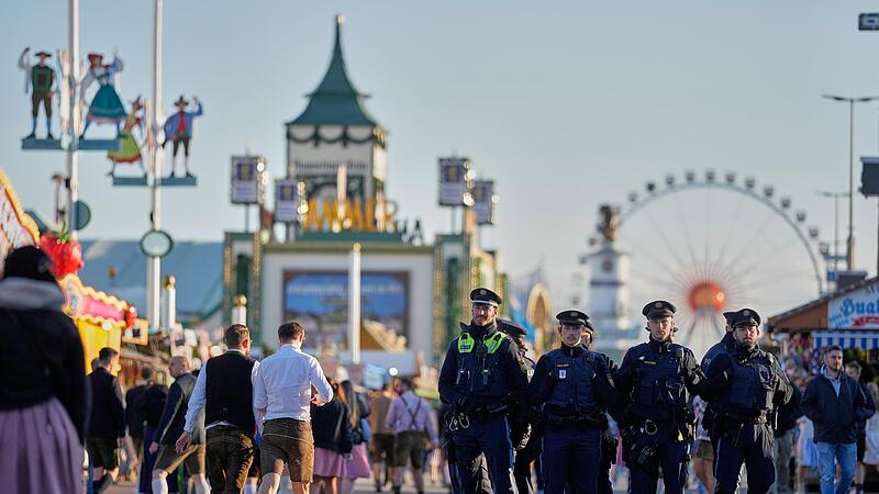 Besucher gehen, beobachtet von Polizeibeamten, nach dem Einlass wieder auf das Gel&auml;nde des Oktoberfests. Nach der Schlie&szlig;ung wegen einer Bombendrohung ist das M&uuml;nchner Oktoberfest am Mittwochabend wieder ge&ouml;ffnet worden.